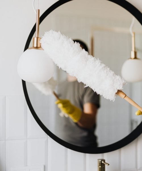 Woman dusting mirror in deep cleaning service